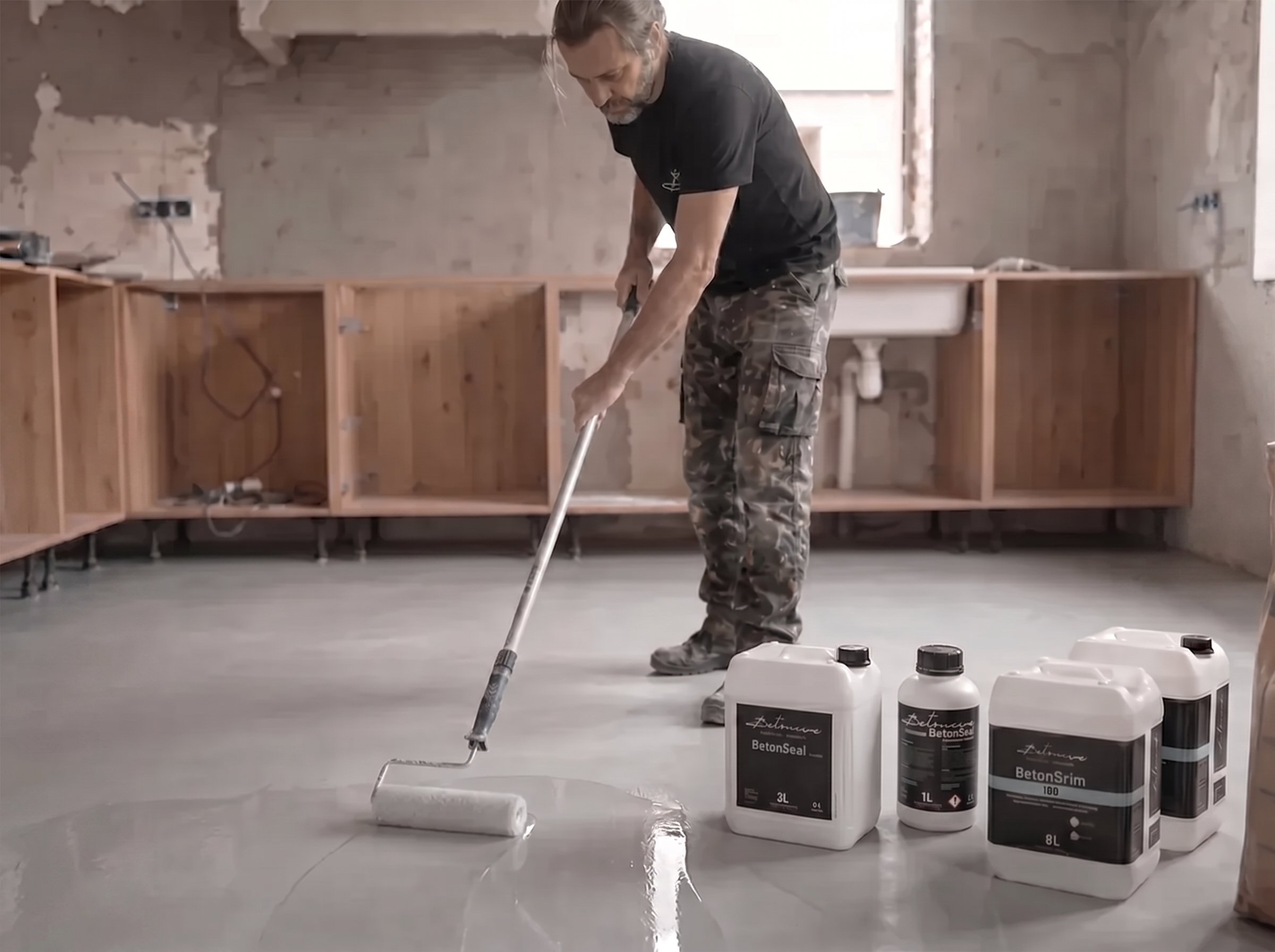 Aplicador profesional sella suelo de microcemento Betoncire con rodillo y BetonSeal, junto a BetonSrim 100, garantizando acabado impermeable y duradero.